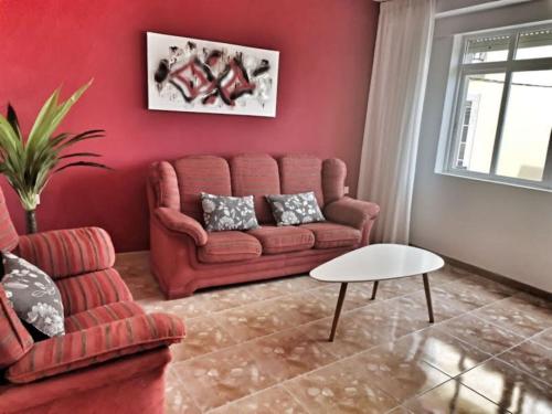 a living room with a red couch and a table at Apto Playa Camelle 1º in Camelle