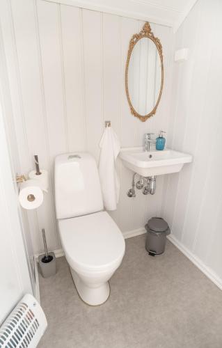 a white bathroom with a toilet and a sink at Husum Hotel in Borgund