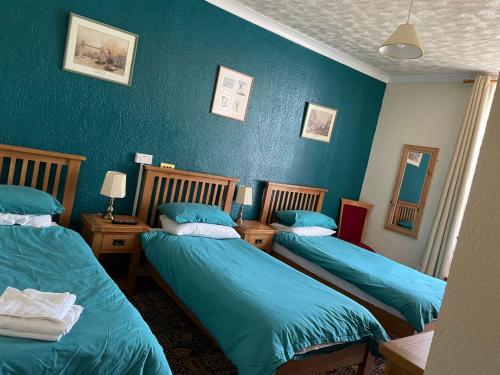 Dinorben Arms Hotel في أمليتش: سريرين في غرفة بجدران زرقاء