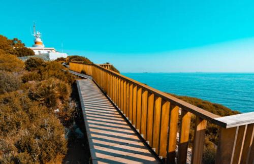 a wooden walkway leading down to the ocean with a lighthouse at Alquiler Vacacional Salou W&S in Salou