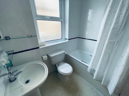 a white bathroom with a toilet and a sink at Merrion Hotel in Llandudno