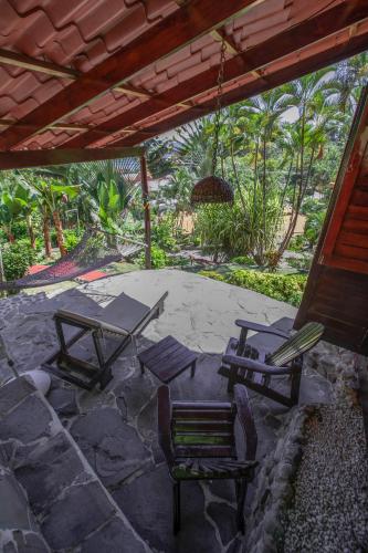 a patio with chairs and a table and a swing at Hotel El Jardin in Montezuma