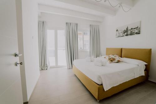 a white bedroom with a large bed with white sheets at Casa Peonia by MONHOLIDAY in Monopoli