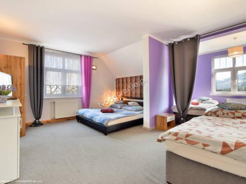 カルパチにあるLawendowy Dworekのベッドルーム(ベッド2台、紫色のカーテン付)