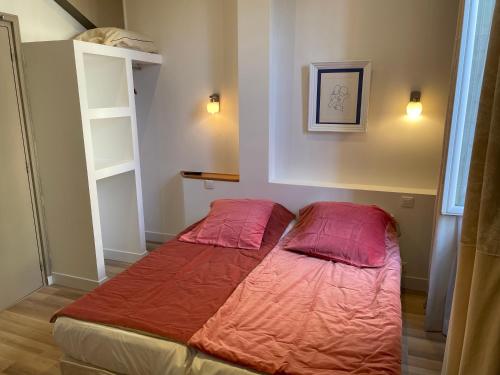 a bed in a room with two pillows on it at Hôtel La Villa Patricia - Charme et Tradition in Villefranche-sur-Mer