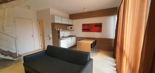 a living room with a black couch and a kitchen at Grand Loft - Amazing Duplex 314 in Sao Paulo
