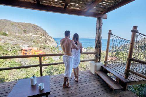 a man and woman standing on a porch looking at the ocean at Casa Roni by Xeno - 5 Bedroom Luxury Villa with Ocean View in Playa Estacahuite