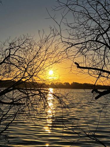 a sunset over a body of water with the sun setting at SWEET APP AM SEE in Pönitz am See