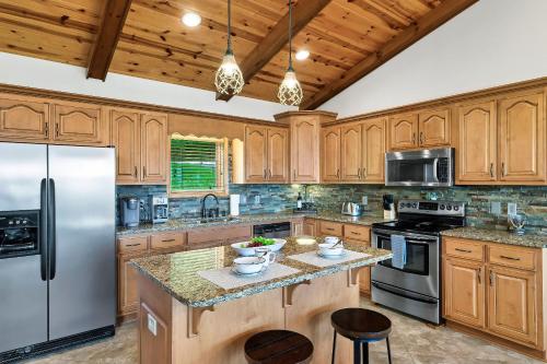 a kitchen with wooden cabinets and a stainless steel refrigerator at Spacious Murphy Cabin with Game Rooms and Mtn Views! in Murphy