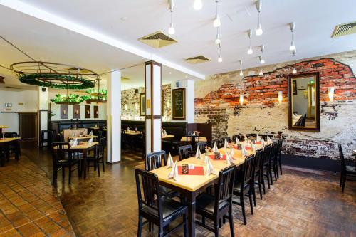 une salle à manger avec des tables et des chaises et un mur en briques dans l'établissement Askania Hotel & Brauhaus, à Bernburg