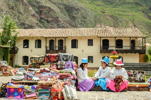 three women in hats sitting in front of a market at Sonesta Posadas del Inca - Valle Sagrado Yucay Urubamba in Urubamba