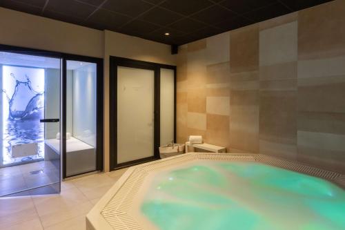 baño con bañera grande y ventana en Best Western Plus Le Conquerant Rouen Nord, en Bois-Guillaume