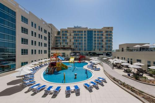a pool with a slide and chairs and buildings at Radisson Resort Ras Al Khaimah Marjan Island in Ras al Khaimah