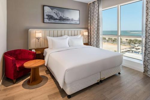 a bedroom with a white bed and a red chair at Radisson Resort Ras Al Khaimah Marjan Island in Ras al Khaimah