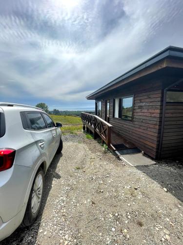 a white car parked next to a small building at Moon River Puerto Varas in Puerto Varas