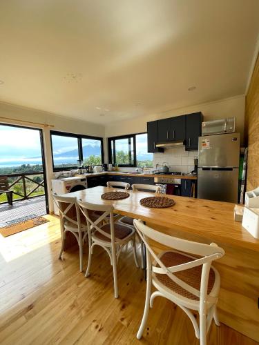 a kitchen with a table and chairs and a kitchen with windows at Moon River Puerto Varas in Puerto Varas