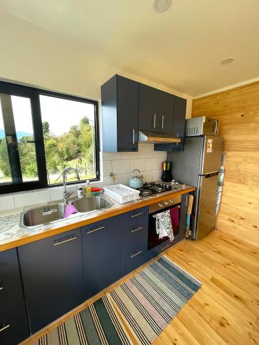 a kitchen with black cabinets and a sink and a window at Moon River Puerto Varas in Puerto Varas