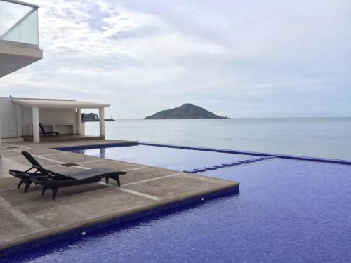 a swimming pool with a bench next to the ocean at Marina del Sol Resort Condo directly on the Ocean 102 in Mazatlán