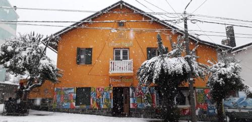 un edificio arancione con la neve davanti di HOPA-Home Patagonia Hostel & Bar a San Carlos de Bariloche