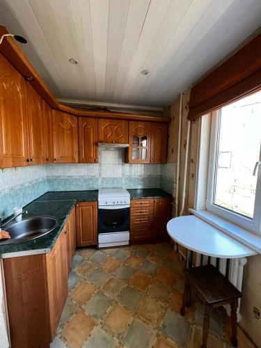 uma cozinha com armários de madeira, um lavatório e uma mesa em Nice and Cosy two bedrooms parking balcony apartment em Riga