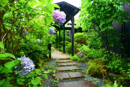a garden with a walkway with purple flowers at Yurari Rokumyo in Yufuin
