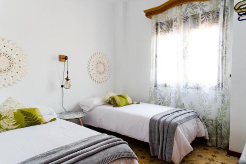 a bedroom with two beds and a window at Ático Imperial GARAJE GRATIS Céntrico Terraza Aire Acond Solarium 2 baños wifi a 1minuto de la Plaza Cabildo in Sanlúcar de Barrameda
