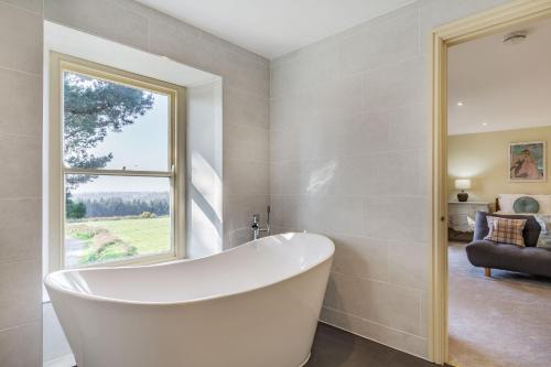 特魯羅的住宿－Tregoninny Vineyard and Woodland Farmhouse，带窗户的浴室内的白色浴缸