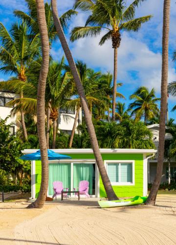 a house on the beach with palm trees and a surfboard at La Siesta Resort & Villas in Islamorada