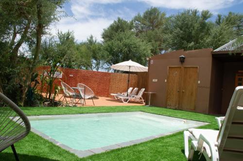 a swimming pool in a yard with chairs and an umbrella at Sami Atacama in San Pedro de Atacama