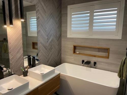 a bathroom with two sinks and a tub and a window at Lakefront Holiday Home in Berkeley Vale