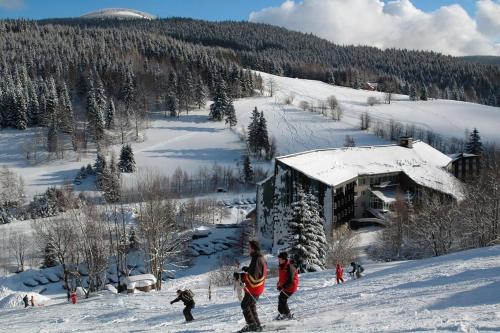 a group of people standing in the snow in front of a building at Hotel Fit Fun in Harrachov