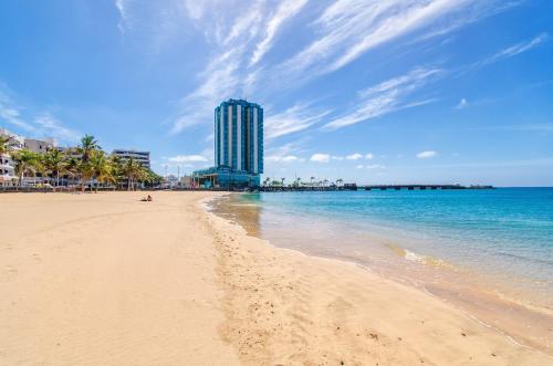 a beach with a tall building in the background at Arrecife Gran Hotel & Spa in Arrecife