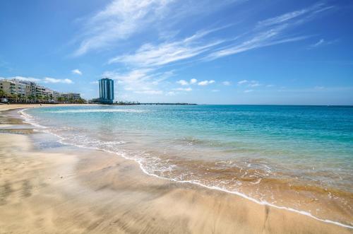 a beach with the ocean and a building in the background at Arrecife Gran Hotel & Spa in Arrecife