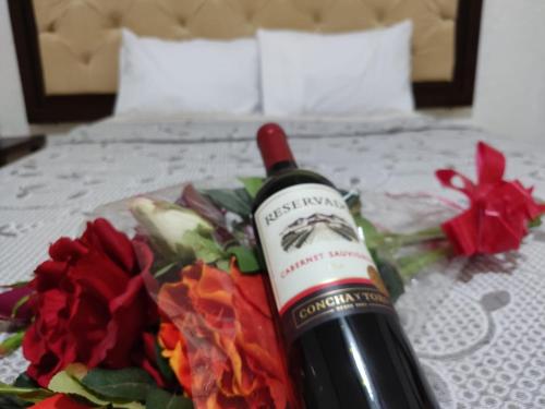 Una botella de vino sentada en una cama con flores en Hotel Peña Florencia, en Bernal