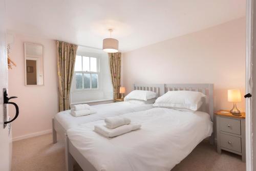 two beds in a bedroom with white sheets and pillows at Rhubarb Cottage in Chapel Stile
