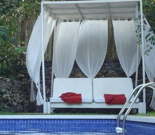 a white couch with red pillows sitting next to a pool at Terra Dos Goitis - Chalés - Pipa in Pipa