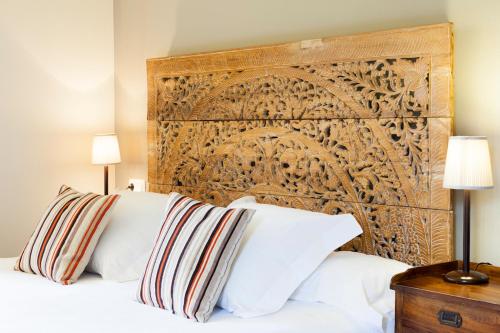 1 cama con almohadas blancas y cabecero de madera en Pazo da Touza, en Nigrán
