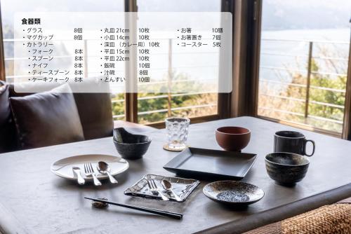 a table with plates and utensils on a table with a window at VILLA HAKONE湖空 in Hakone