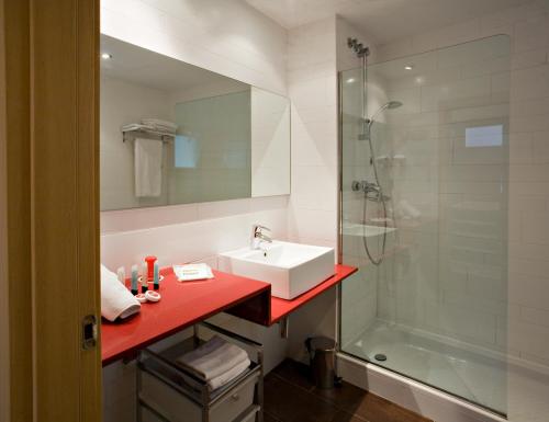y baño con encimera roja, lavabo y ducha. en Apartaments Ciutat Vella en Barcelona