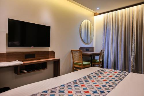 a hotel room with a bed and a flat screen tv at Suvidha Suites in Vasai