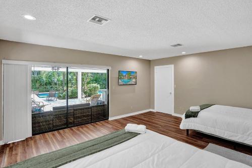 1 dormitorio con cama y vistas a un patio en Modern 6br Villa Resort Style Pool On Golf Course en Pompano Beach