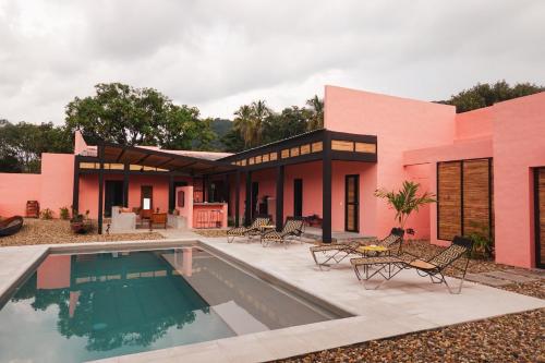 a pink house with a swimming pool in front of it at Casa De Amigos Hotel Boutique in Honda