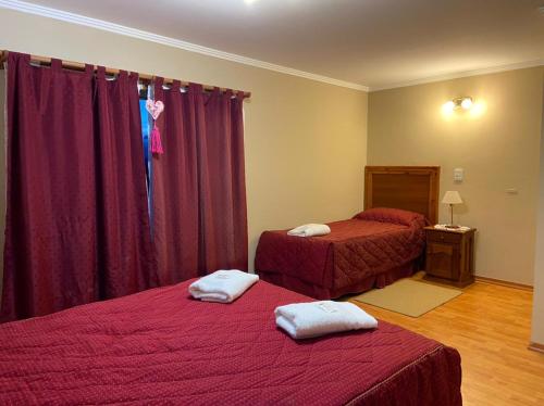 een slaapkamer met 2 bedden met rode lakens en witte handdoeken bij lavanda I in El Calafate