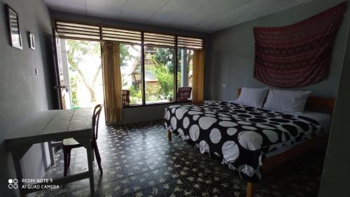 a bedroom with a bed and a table and a window at Leokap Homestay in Tuk Tuk