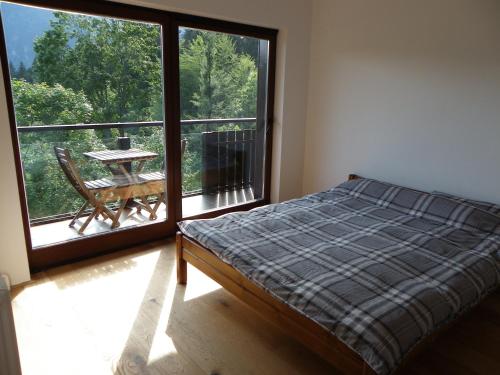 a bedroom with a bed and a balcony with a table at Triglav Park House in Bled