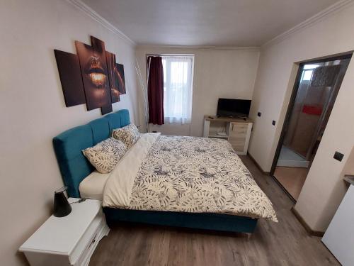 a bedroom with a bed with a blue headboard at Apartment First December in Oradea