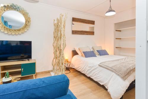 sypialnia z łóżkiem, telewizorem i niebieską kanapą w obiekcie Bien-être et bonheur au pied des Thermes w mieście Allevard
