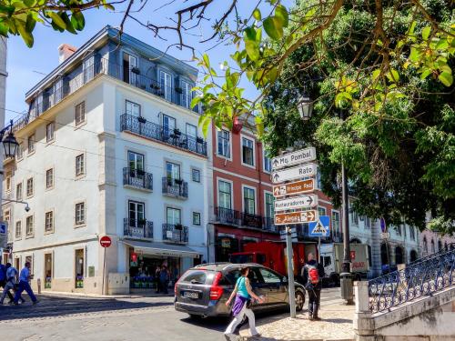 a woman walking down a city street with a building at Residentas Sao Pedro in Lisbon