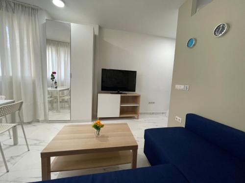 sala de estar con sofá azul y TV en El Oasis de SteraM Flats Torremolinos, en Torremolinos