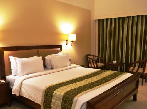 a hotel room with a large bed and chairs at Uday Suites - The Airport Hotel in Trivandrum